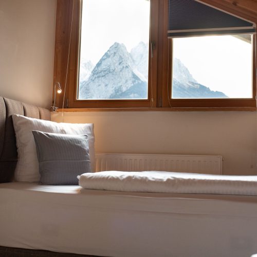 Einzelbett mit Ausblick auf die Alpen in Ferienwohnung in Garmisch-Partenkirchen