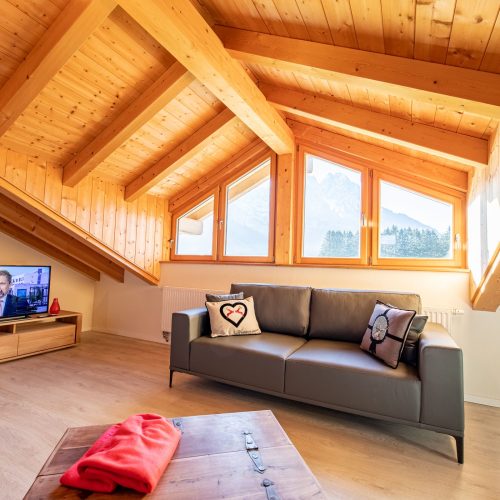 Wohnzimmer mit Sofa und Fernseher in Ferienwohnung in Garmisch-Partenkirchen