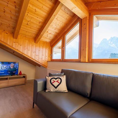 Wohnbereich mit Fernseher und Sofa in Ferienwohnung in Garmisch-Partenkirchen