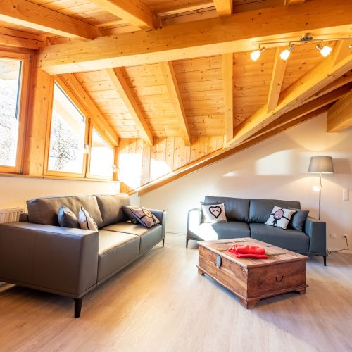 Wohnzimmer mit zwei schwarzen Sofas und einem Holztisch in Ferienwohnung in Garmisch-Partenkirchen
