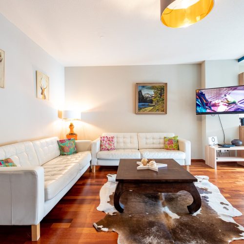 Wohnzimmer mit weißen Wänden und einer weißen Couch in Ferienwohnung in Garmisch-Partenkirchen