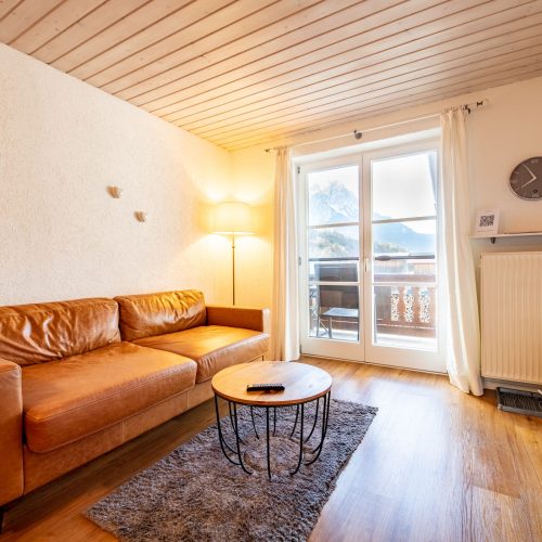 Wohnbereich mit Uhr und Fernseher in Ferienwohnung in Garmisch-Partenkirchen