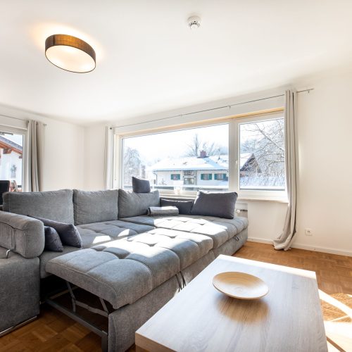 Wohnzimmer mit Couchtisch und grauem Sofa in Ferienwohnung in Garmisch-Partenkirchen