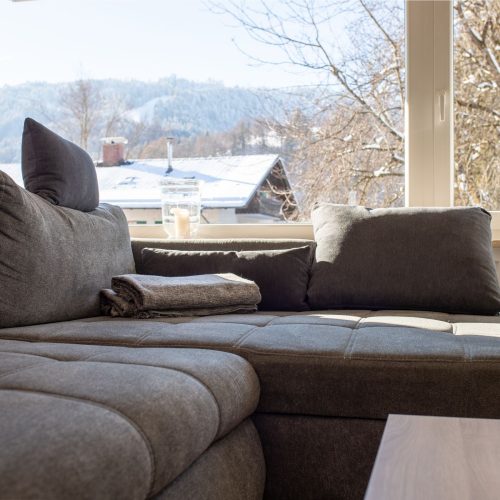 Sofa in grau mit großem Fenster in Ferienwohnung in Garmisch-Partenkirchen
