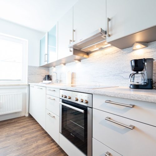 Küche mit hellrauer Arbeitsfläche und Ofen in Ferienwohnung in Garmisch-Partenkirchen