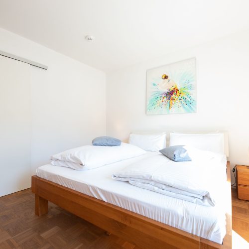 Doppelbett mit einem farbenfrohen Bild in Ferienwohnung in Garmisch-Partenkirchen