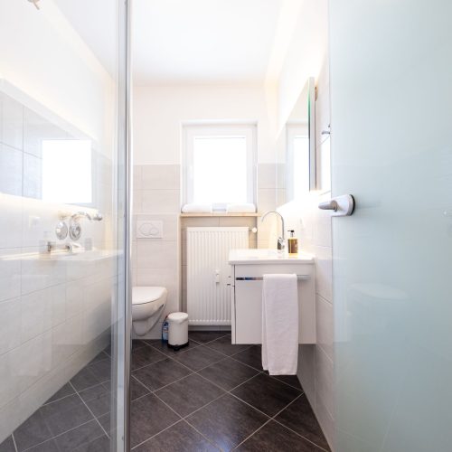 Badzimmer mit schwarzen Fliesen und weißem Waschbecken in Ferienwohnung in Garmisch-Partenkirchen