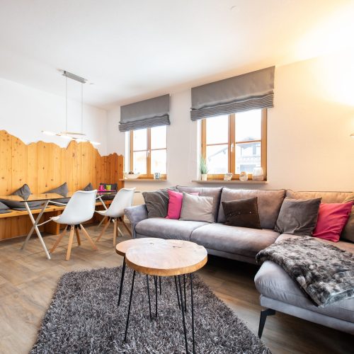 Sofa mit Kissen und Flauschdecke und Stehlampe in Ferienwohnung in Garmisch-Partenkirchen