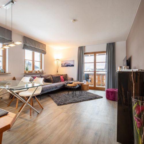 Wohnbereich mit Esstisch und Stühlen und einem Sofa und Fernseher in Ferienwohnung in Garmisch-Partenkirchen