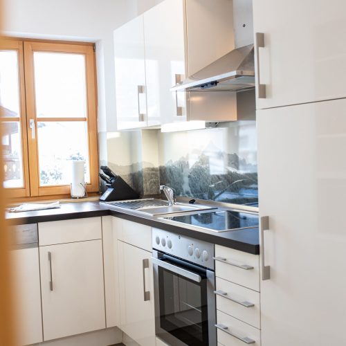 Küche in weiß mit Herd und Ofen in Ferienwohnung in Garmisch-Partenkirchen