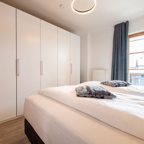 Doppelbettzimmer mit einem großen Kleiderschrank und grauen Gardienen in Ferienwohnung in Garmisch-Partenkirchen
