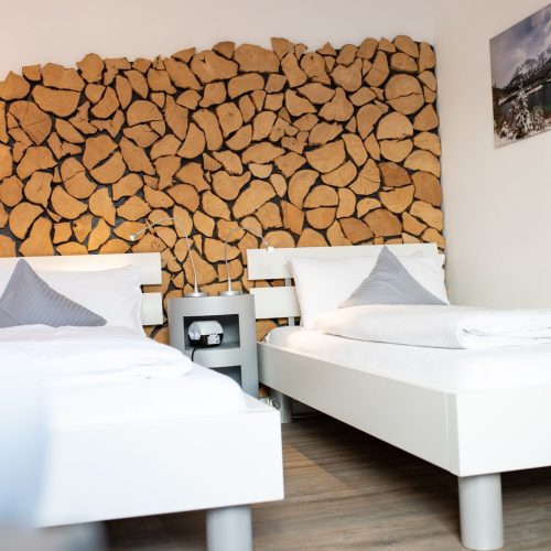 zwei Einzelbetten mit einer Holz gemusterten Wand und einem Landschaftsbild in Ferienwohnung in Garmisch-Partenkirchen