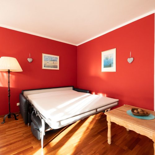 Schlafsofa mit roter Wand in Ferienwohnung in Garmisch-Partenkirchen