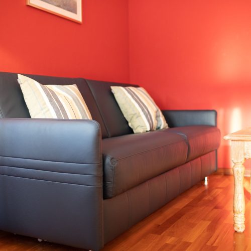 schwarzes Sofa mit Kissen und rote Wand in Ferienwohnung in Garmisch-Partenkirchen