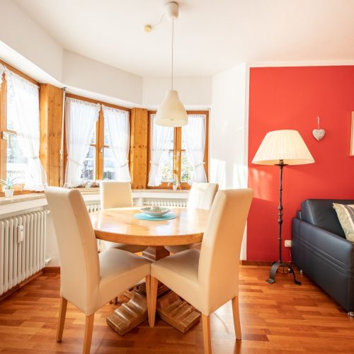 Esstisch mit Stühlen und roter Wand in Ferienwohnung in Garmisch-Partenkirchen