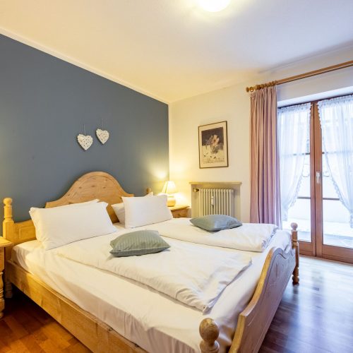 Doppelbett mit blauer Wand in Ferienwohnung in Garmisch-Partenkirchen