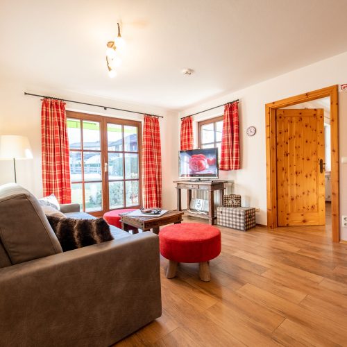Wohnzimmer mit rot Tönen und grauem Sofa in Ferienwohnung in Garmisch-Partenkirchen