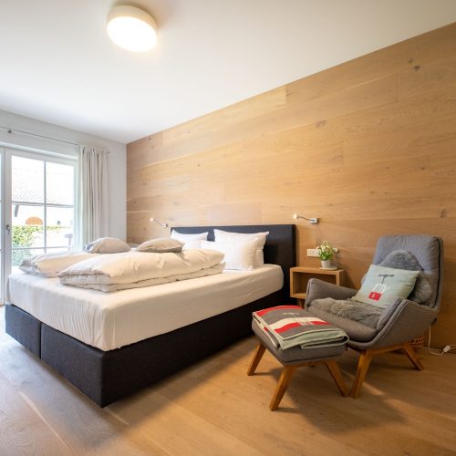 Schlafzimmer mit großer Holzwand und Holzboden in Ferienwohnung in Garmisch-Partenkirchen
