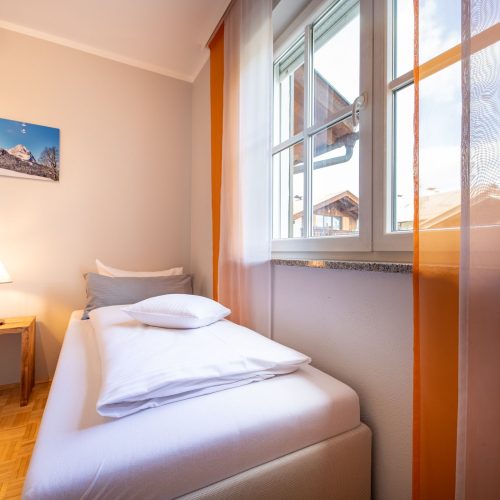 Einzelbett und Fenster in Ferienwohnung in Garmisch-Partenkirchen
