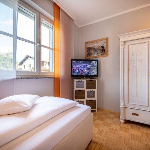Schlafzimmer mit Fernseher und Schrank in Ferienwohnung in Garmisch-Partenkirchen