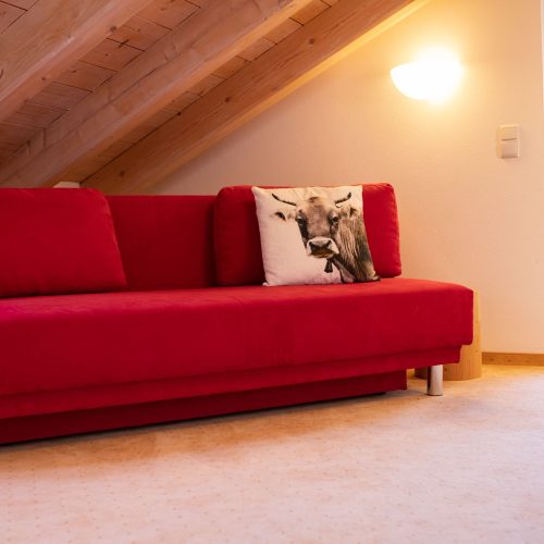 Rotes Sofa mit Kuhkissen in Ferienwohnung in Garmisch-Partenkirchen