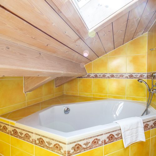 Gelb gefliestes Badezimmer mit Badewanne in Ferienwohnung in Garmisch-Partenkirchen
