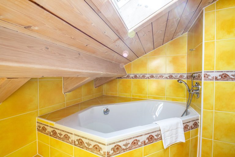 Gelb gefliestes Badezimmer mit Badewanne in Ferienwohnung in Garmisch-Partenkirchen