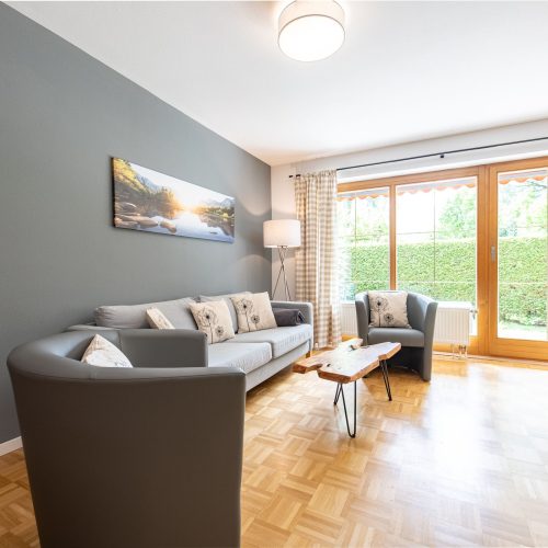 Wohnbereich mit zwei grauen Sesseln und Sofa in Ferienwohnung in Garmisch-Partenkirchen