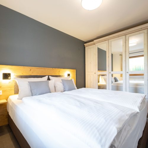 Doppelbett mit großem Holzschrank und Spiegeln in Ferienwohnung in Garmisch-Partenkirchen