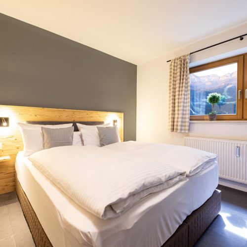 Doppelbett im Schlafzimmer mit schönem Ausblick in Ferienwohnung in Garmisch-Partenkirchen