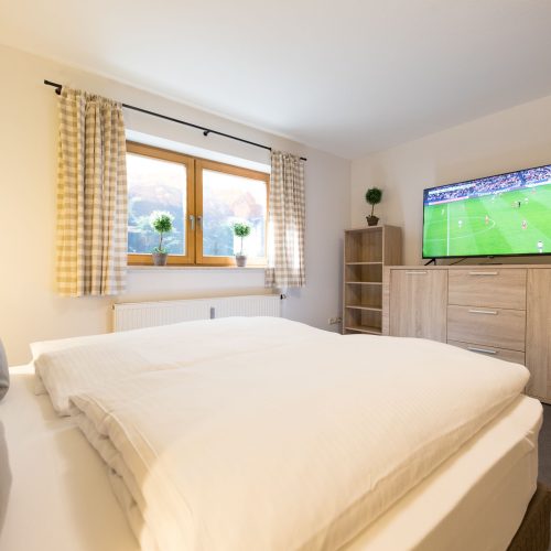 Doppelbett mit großem Fernseher auf Holzschrank in Ferienwohnung in Garmisch-Partenkirchen