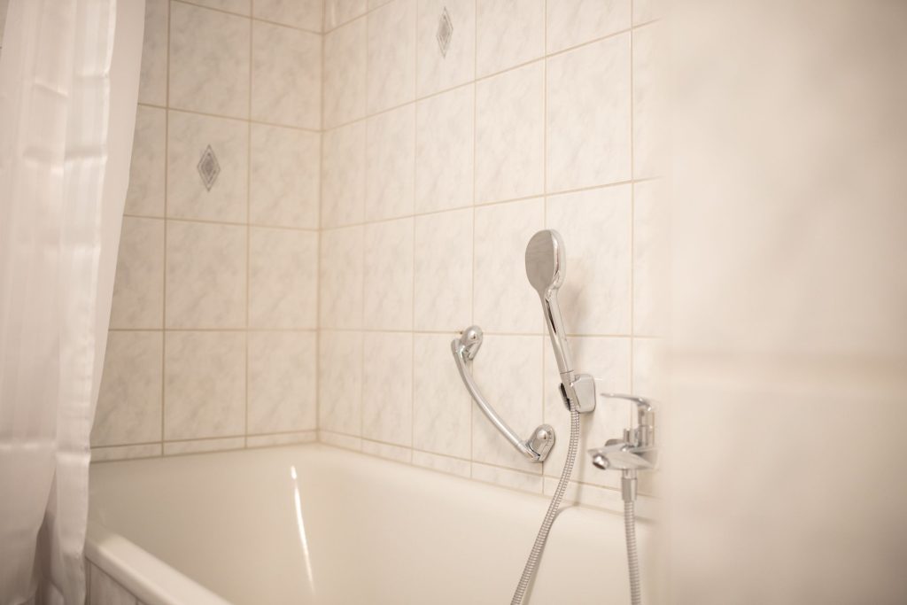 Hell gefliestes Bad mit Badewanne und Duschfunktion in Ferienwohnung in Garmisch-Partenkirchen