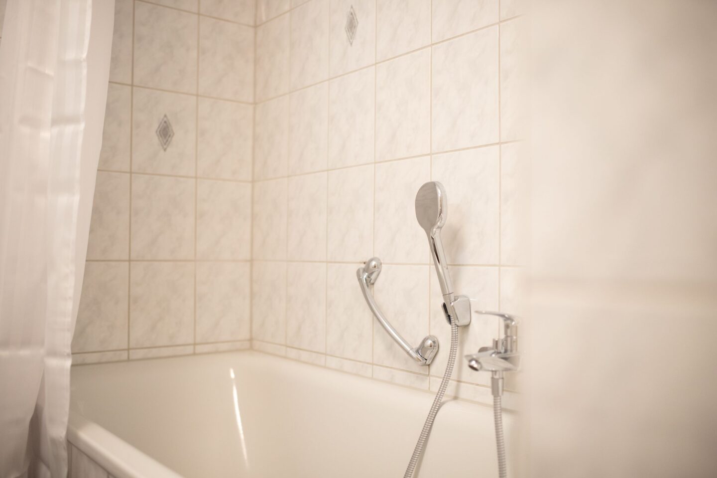 Hell gefliestes Bad mit Badewanne und Duschfunktion in Ferienwohnung in Garmisch-Partenkirchen