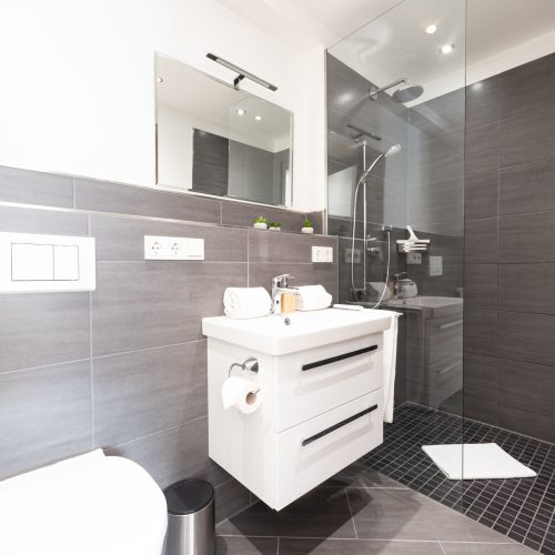 Modernes Badezimmer mit dunklen Fliesen in Ferienwohnung in Garmisch-Partenkirchen