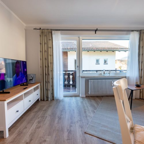 Blick aus den Wohnbereich auf Fernseher und Balkon