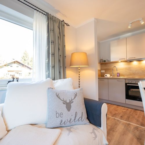Wohnbereich mit Sofa und Blick auf die Küche in Ferienwohnung in Garmisch-Partenkirchen