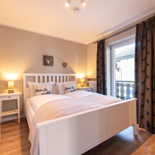 Schlafzimmer mit Doppelbett und Gardinen mit Hirsch-Gardinen in Ferienwohnung in Garmisch-Partenkirchen