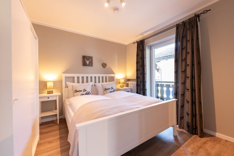 Schlafzimmer mit Doppelbett und Gardinen mit Hirsch-Gardinen in Ferienwohnung in Garmisch-Partenkirchen