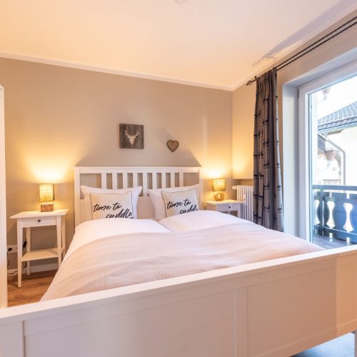 Schlafzimmer mit Doppelbett und Zugang zum Balkon in Ferienwohnung in Garmisch-Partenkirchen