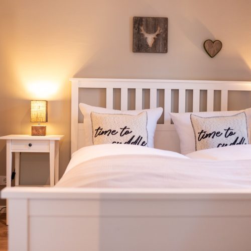 Doppelbett mit kleinen Nachttischlampen in Ferienwohnung in Garmisch-Partenkirchen