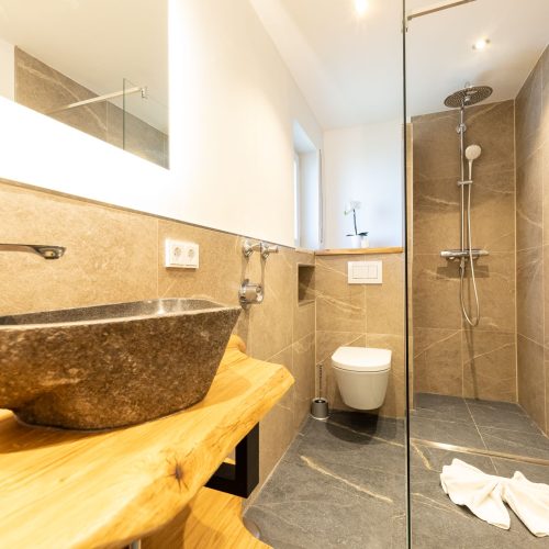 Braun gefliestes Badezimmer mit Dusche und Toilette in Ferienwohnung in Garmisch-Partenkirchen