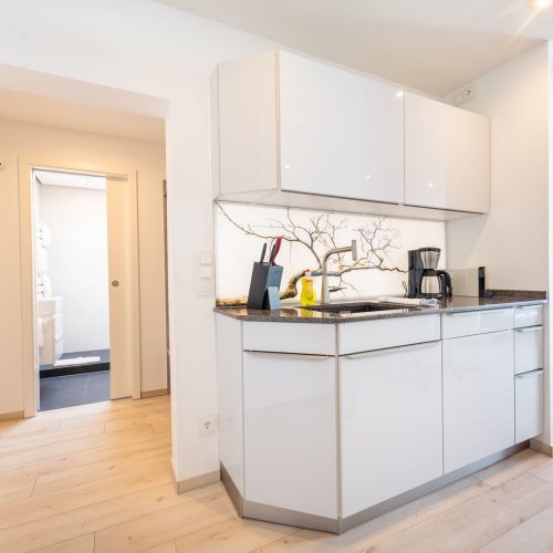 Blick von der Küche ins Bad Weiß-helle Küche in Ferienwohnung in Garmisch-Partenkirchen