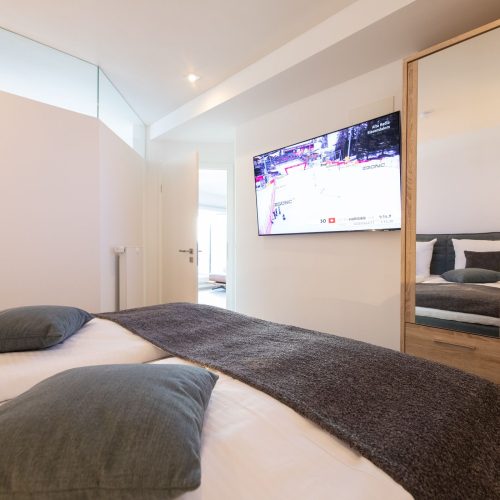 Schlafzimmer mit Holzschrank und Fernseher in Ferienwohnung in Garmisch-Partenkirchen