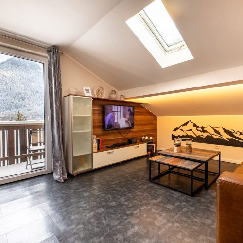 Wohnzimmer mit Fernseher und Dachfenster in Ferienwohnung in Garmisch-Partenkirchen