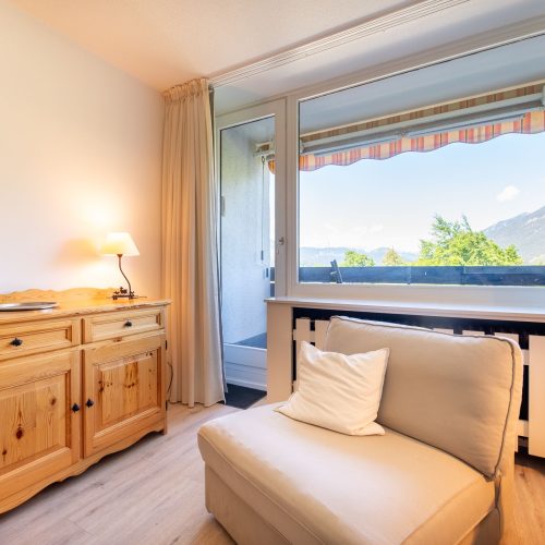 Heller Sessel und Blick zum Fenster in Ferienwohnung in Garmisch-Partenkirchen