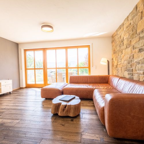 Wohnzimmer mit braunem Sofa und einem Fernseher in Ferienwohnung in Garmisch-Partenkirchen