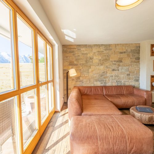 Wohnzimmer mit einer Steinwand und einem braunen Sofa in Ferienwohnung in Garmisch-Partenkirchen