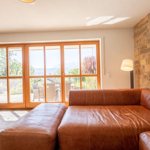 Wohnzimmer mit braunem Sofa und Ausblick auf die Terrasse in Ferienwohnung in Garmisch-Partenkirchen