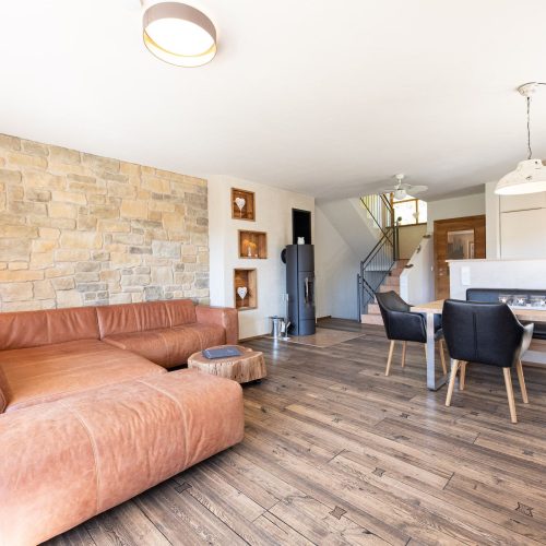 Wohnbereich mit einem braunen Sofa, einem Esstisch, einem Kamin und einer offenen Küche in Ferienwohnung in Garmisch-Partenkirchen