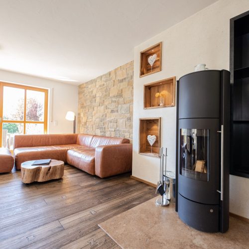 Wohnzimmer mit braunem Sofa und Kamin in Ferienwohnung in Garmisch-Partenkirchen